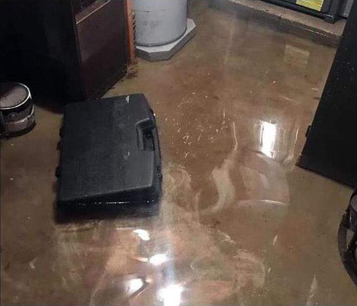 Standing water on the floor, black tool box on standing water. Concept of water damage and flooded basement
